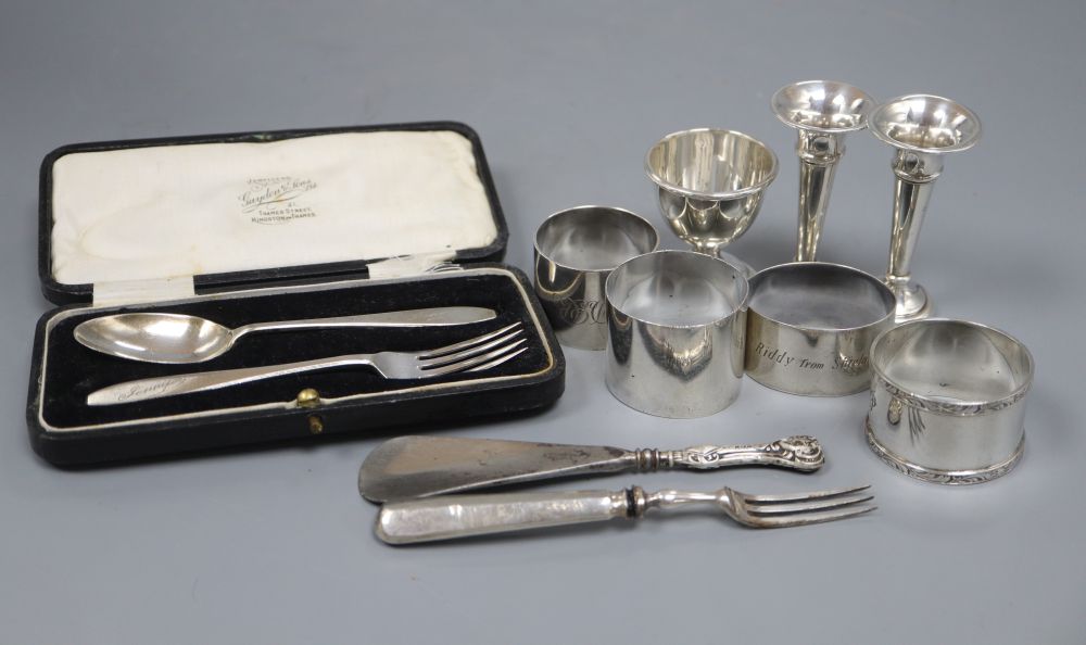 Four silver napkin rings, a silver egg cup, two small silver vases, a cased silver christening pair and two other items,